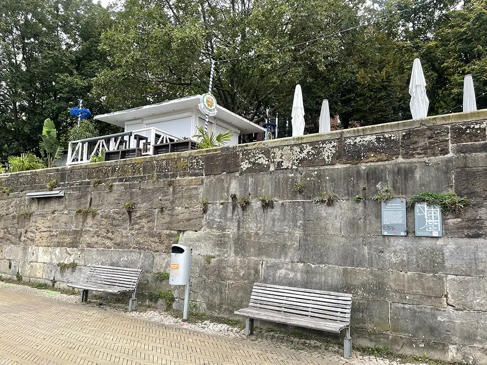 Mauer an der Schlachte, oben ist noch das Gebäude und die eingeklappten Schirme eines Biergartens zu sehen