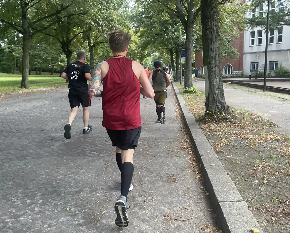 Halbmarathon-Läufer auf baumumstandener Straße mit kleinem Kopfsteinpflaster