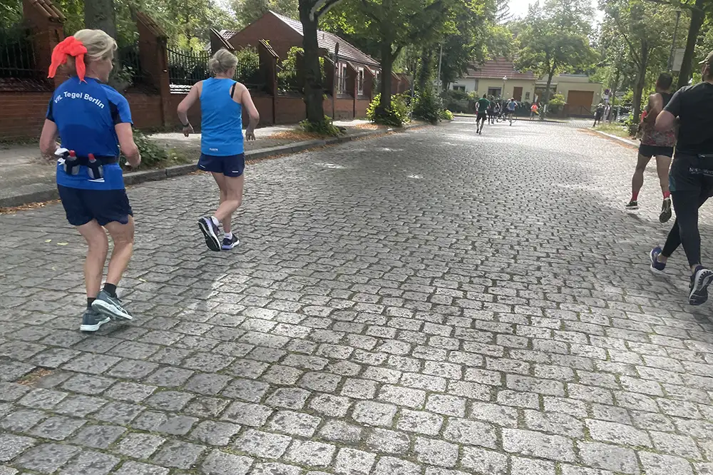 Läuferinnen und Läufer auf Kopfsteinpflaster-Straße