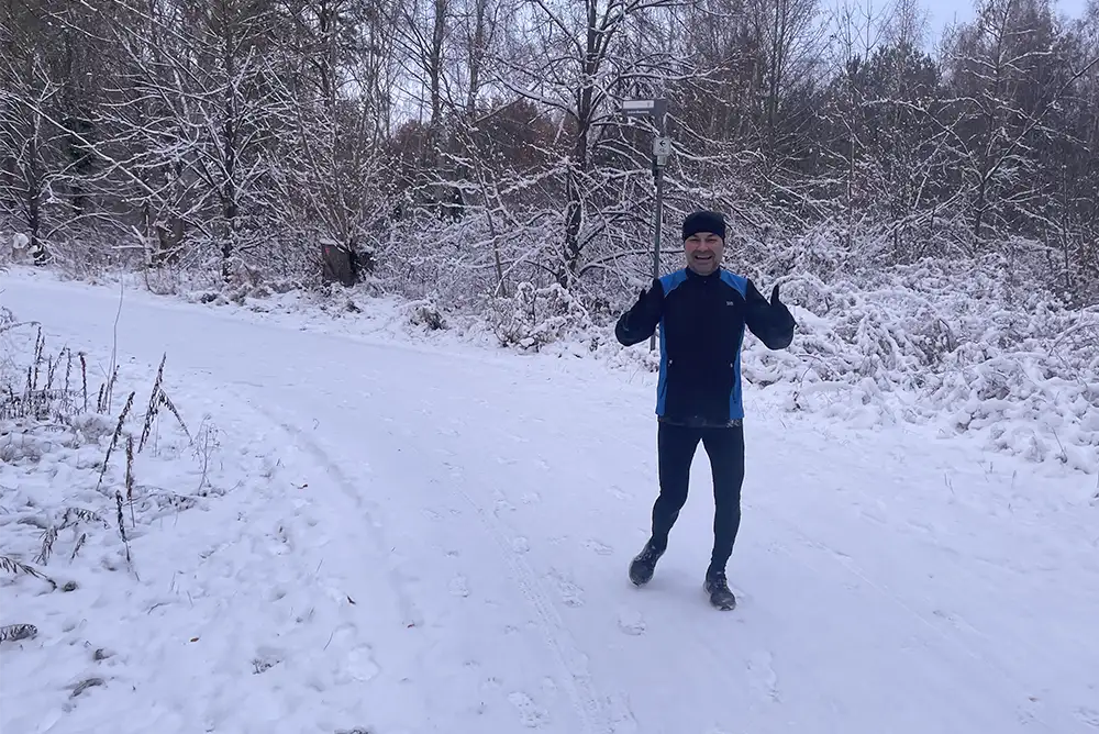 Läufer im Schnee, hält beide Daumen hoch