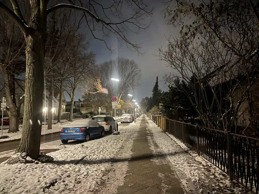 Sich bis zum Horizont hinziehende Wohnstraße mit Schnee und Straßenlaternen