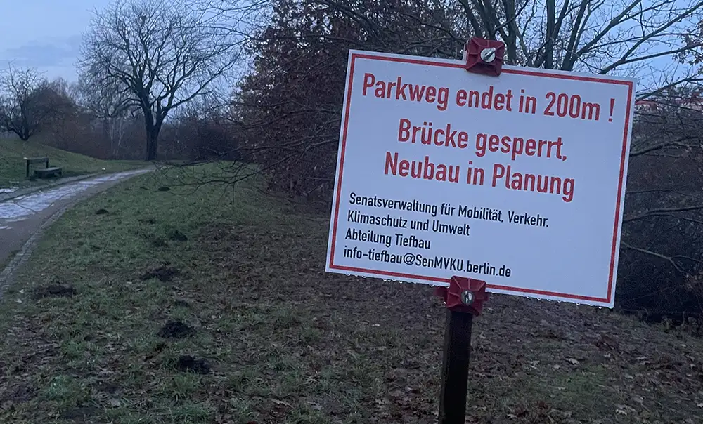 Provisorisch aufgestelltes Hinweisschild „Parkweg endet in 200m! Brücke gesperrt, Neubau in Planung“