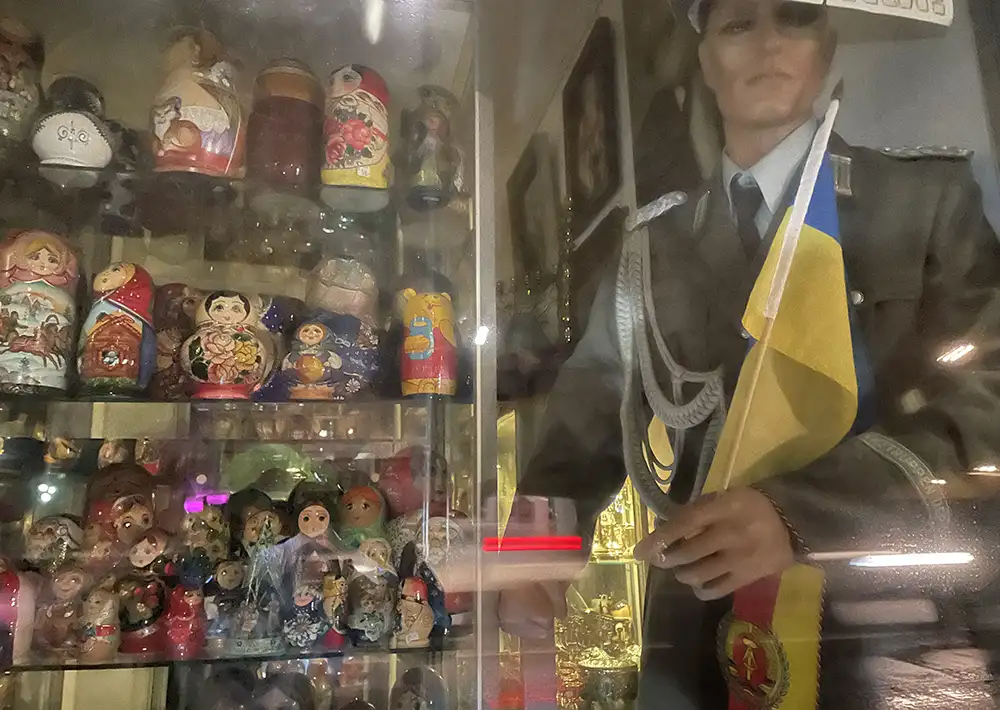 Schaufenster mit russischen Matrjoschkas und einer Schaufensterpuppe in Uniform mit DDR- und Ukraine-Flagge