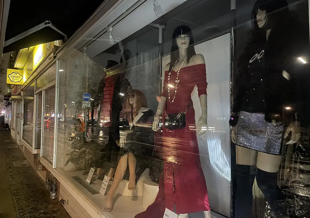 Schaufenster mit weiblichen Schaufensterpuppen, eine in langem rotem Kleid und eine im silber glitzerndem Minirock