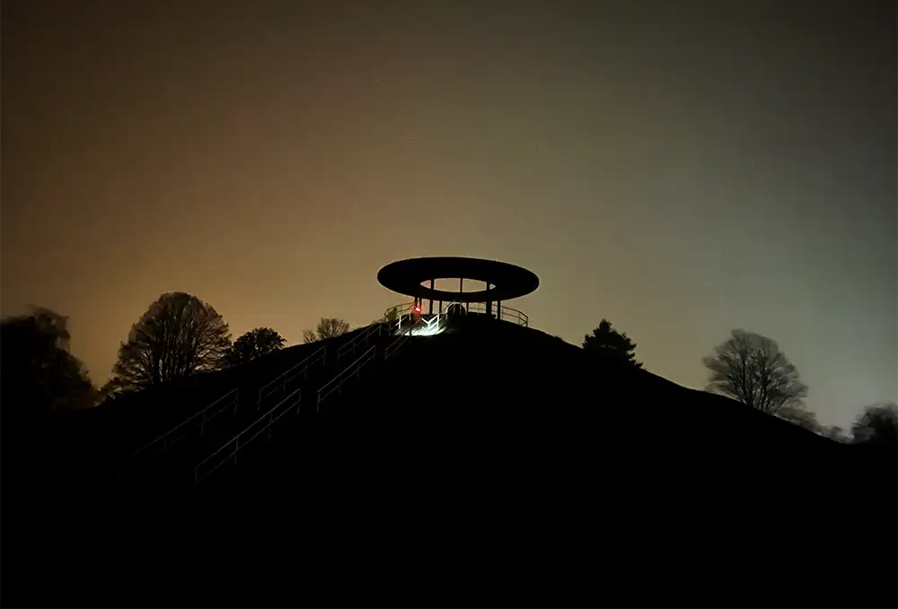 Spitze des Lilienthal-Denkmal-Hügels im Halbdunkel mit Lichtkegel einer Läufer-Stirnlampe