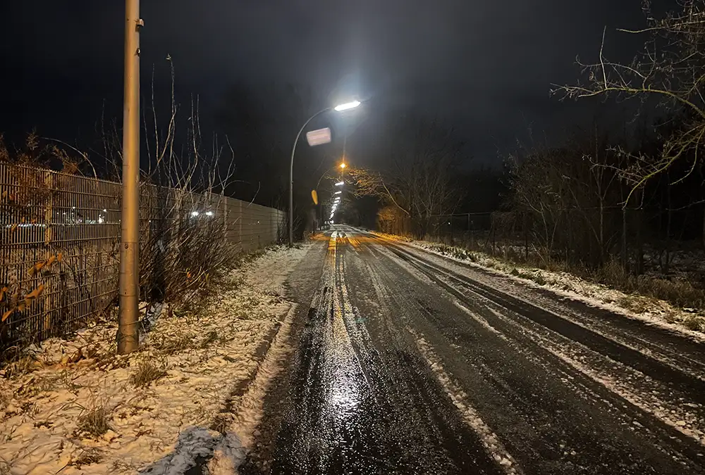 Diedersdorfer Weg mit Eis und Schneematsch auf der Straße im Laternenlicht