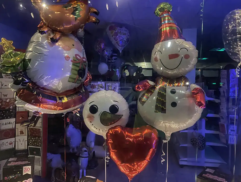 Luftballons in verschiedenen Formen im Schaufenster eines Geschäfts: Weihnachtsmann, Schneemann und Herz