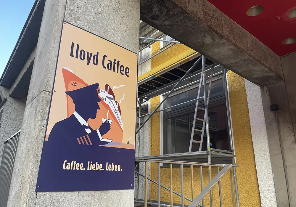 Schild Lloyd Caffee – Caffee. Liebe. Leben. mit Illustration eines großen Schiffes und eines Kapitäns mit Kaffeetasse