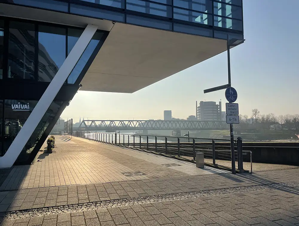 Blick unter dem Überbau eines Bürogebäudes auf die Weser und eine Eisenbahnbrücke