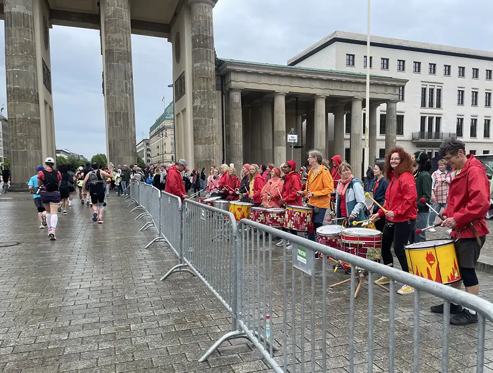 Tropmmelgruppe, gekleidet in rot und orange, am Brandenburger Tor
