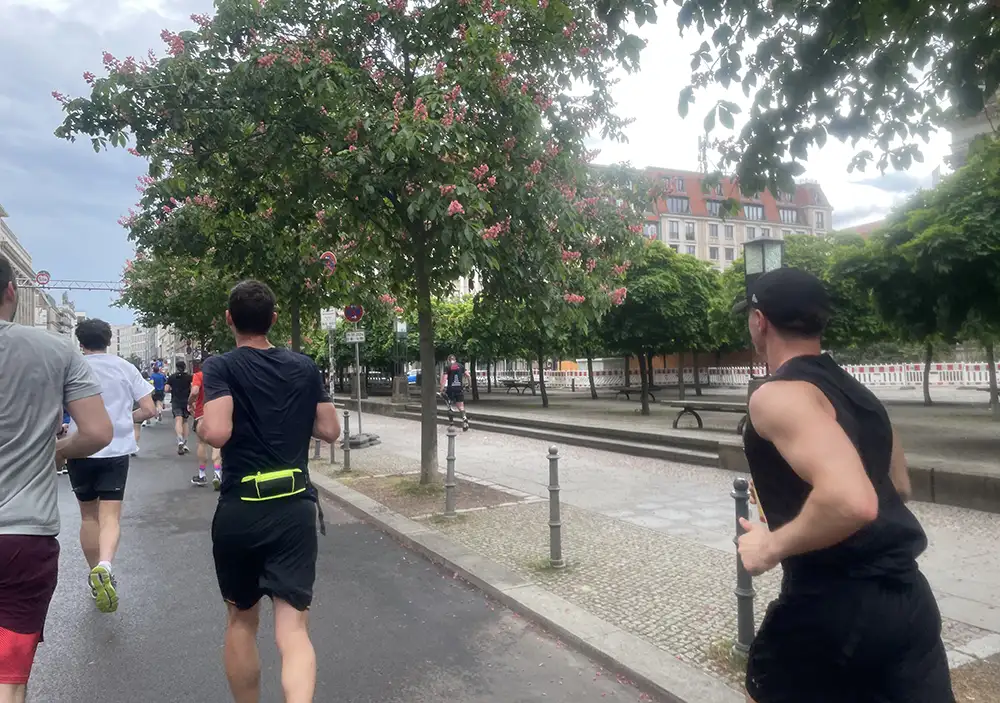 Läufer laufen am Gendarmenmarkt vorbei an blühenden Kastanienbäumen