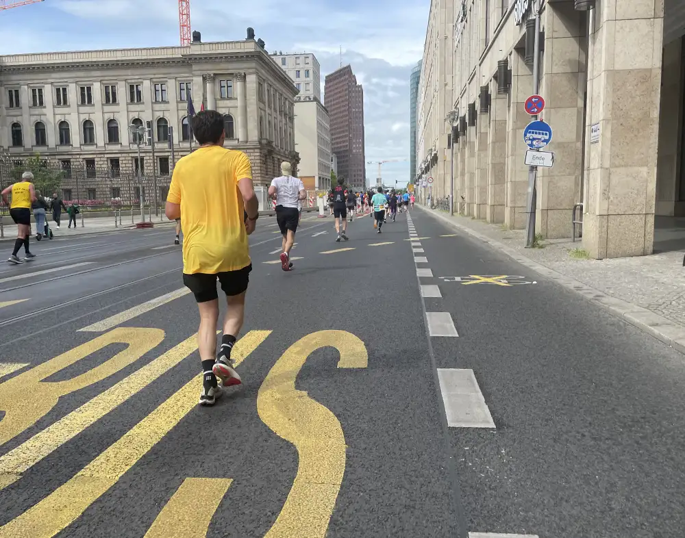 Läufer auf dem Weg zum Potsdamer Platz, auf der Straße eine große gelbe Schrift BUS