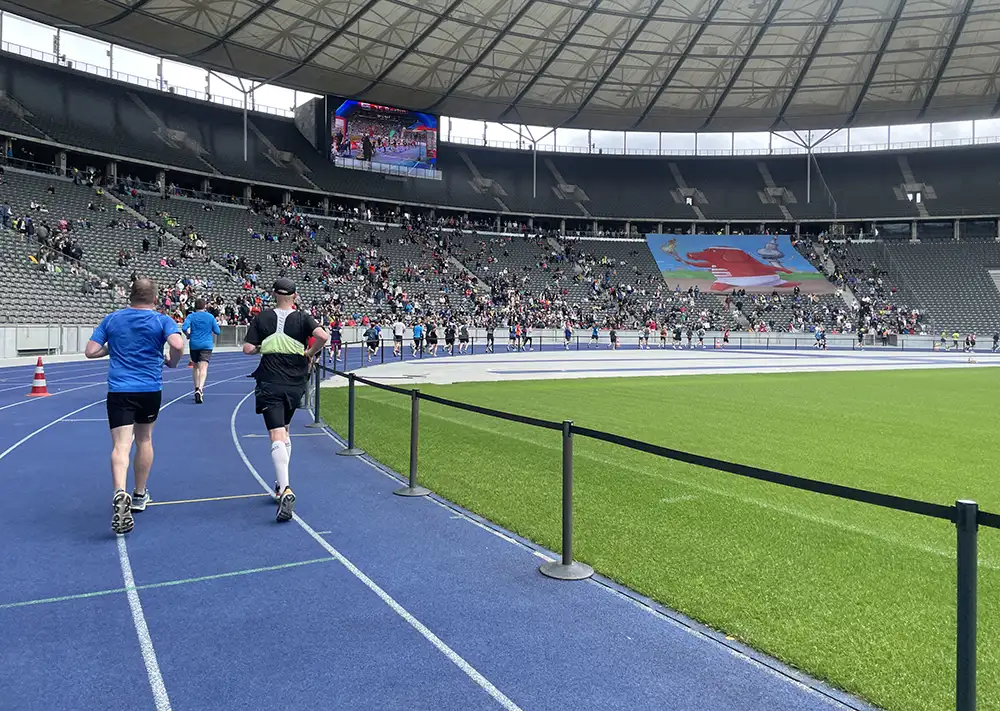 Läuferinnen und Läufer auf der blauen Laufbahn im Olympiastadion