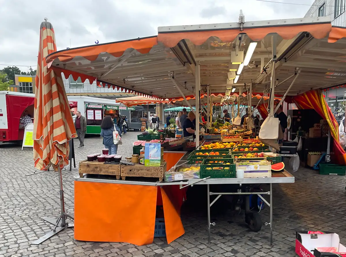 Marktstand mit Obst und Marmeladen und oranger Markise