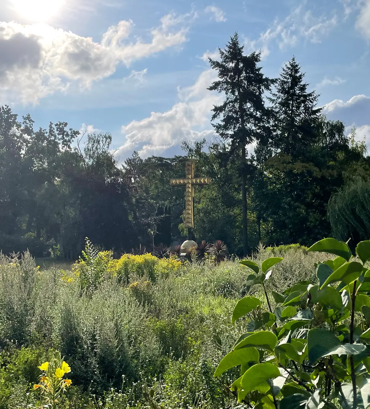 Großes goldenes Kreuz in einer grünen Umgebung