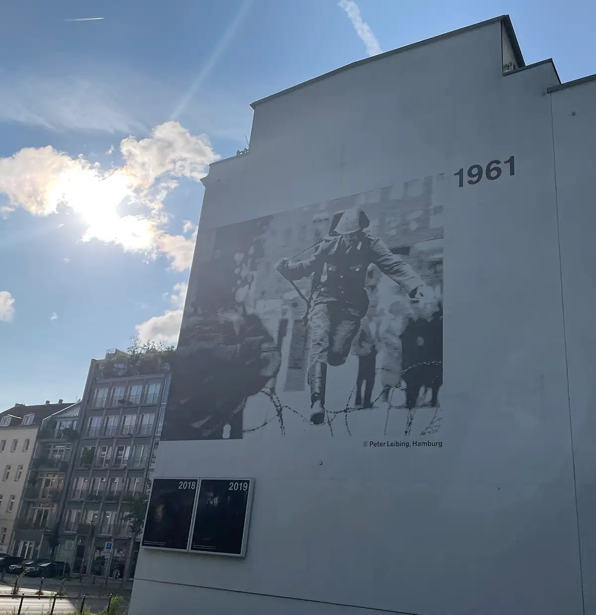 Großes an eine Häuserfassade übertragenes Foto mit dem Motiv des über den Stacheldraht springenden DDR-Grenzsoldaten von 1961