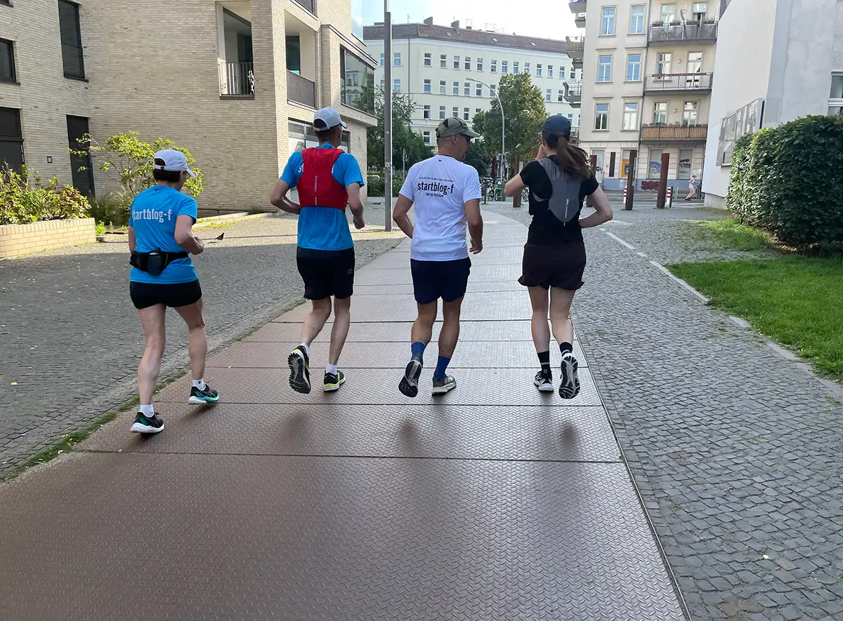 Vier Läuferinnen und Läufer auf Metallplatten, die den Verlauf des ehemaligen Postenwegs markieren