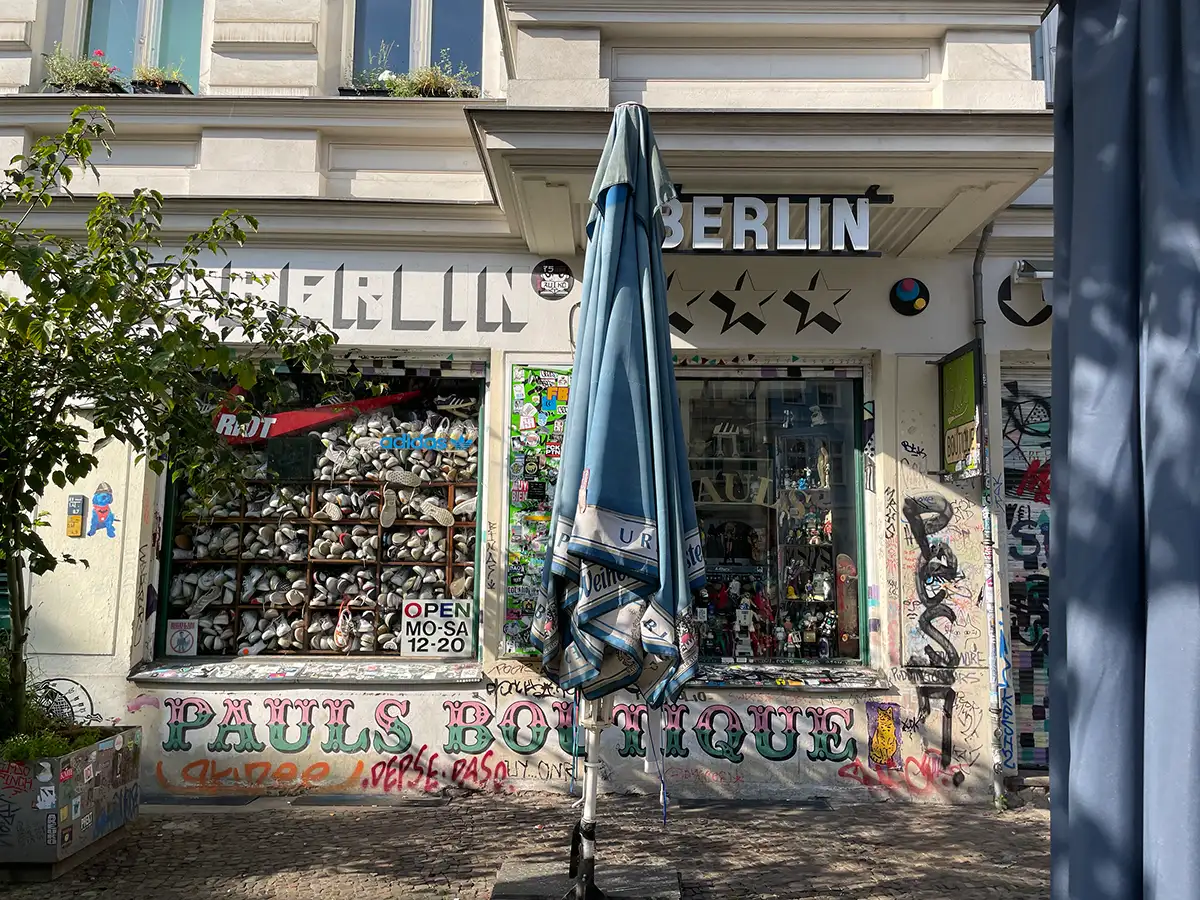 Ladengeschäft mit Beschriftung Berlin und Pauls Boutique und einem Schaufenster, das vollgestapelt ist mit alten weißen Turnschuhen