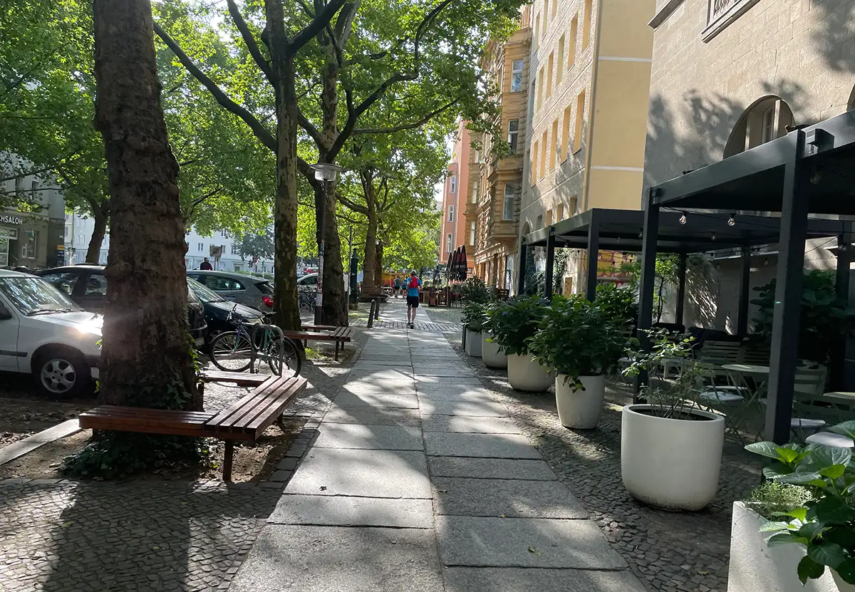 Läufer auf dem mit großen schattigen Bäumen gesäumten Fußweg der Oderberger Straße