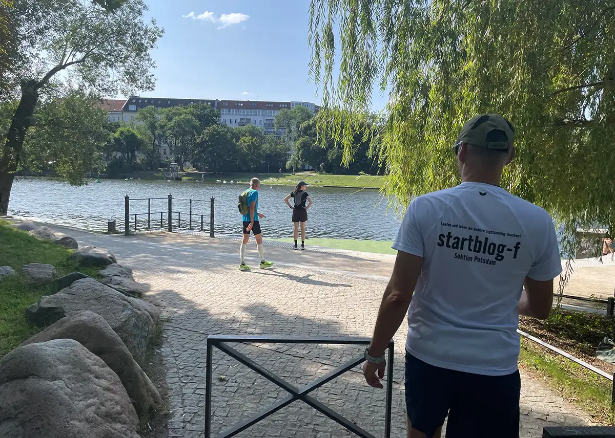 Läufer stehen an der Promenade und schauen auf das Wasser