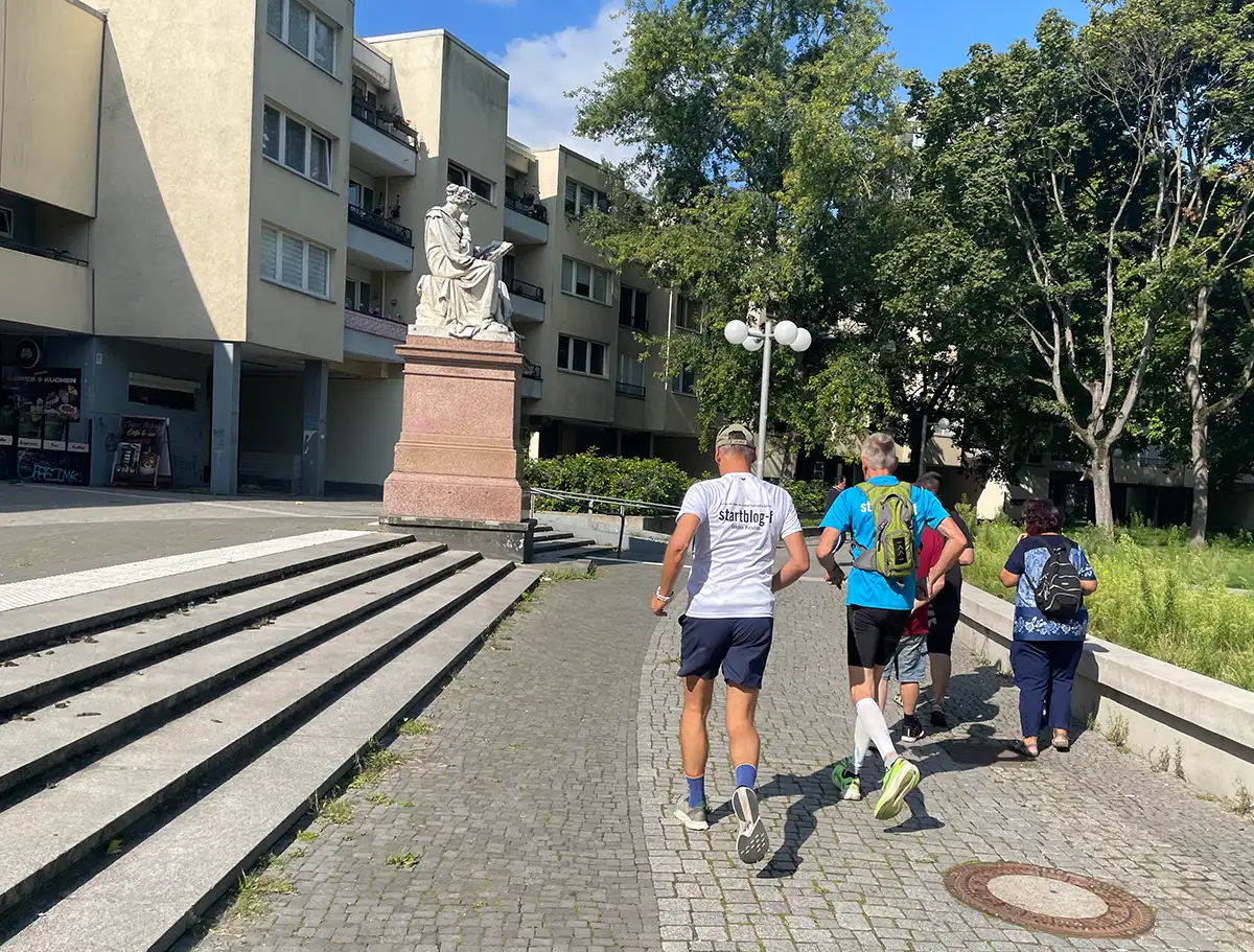 2 Läufer laufen an einer Statue am Mehringplatz vorbei