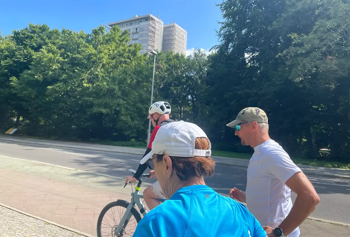 Läufer, Läuferin und Radbegleiter vor einem Hochhaus im Hansaviertel
