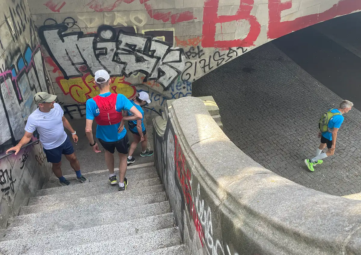 Läufer steigen eine Steintreppe an einer Brücke hinunter