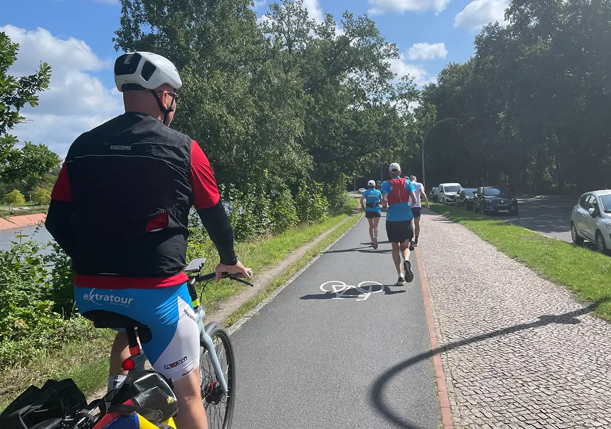 Radbegleiter fährt langsam hinter Laufgruppe her