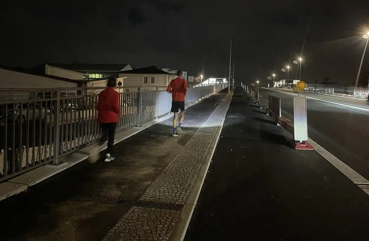 Läuferin und Läufer im Dunkeln auf einer neu gebauten Brücke