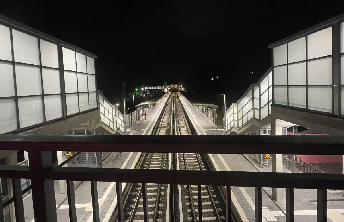 Blick in der Morgendunkelheit auf die hell erleuchteten Gleise, Bahnsteige und Aufgänge