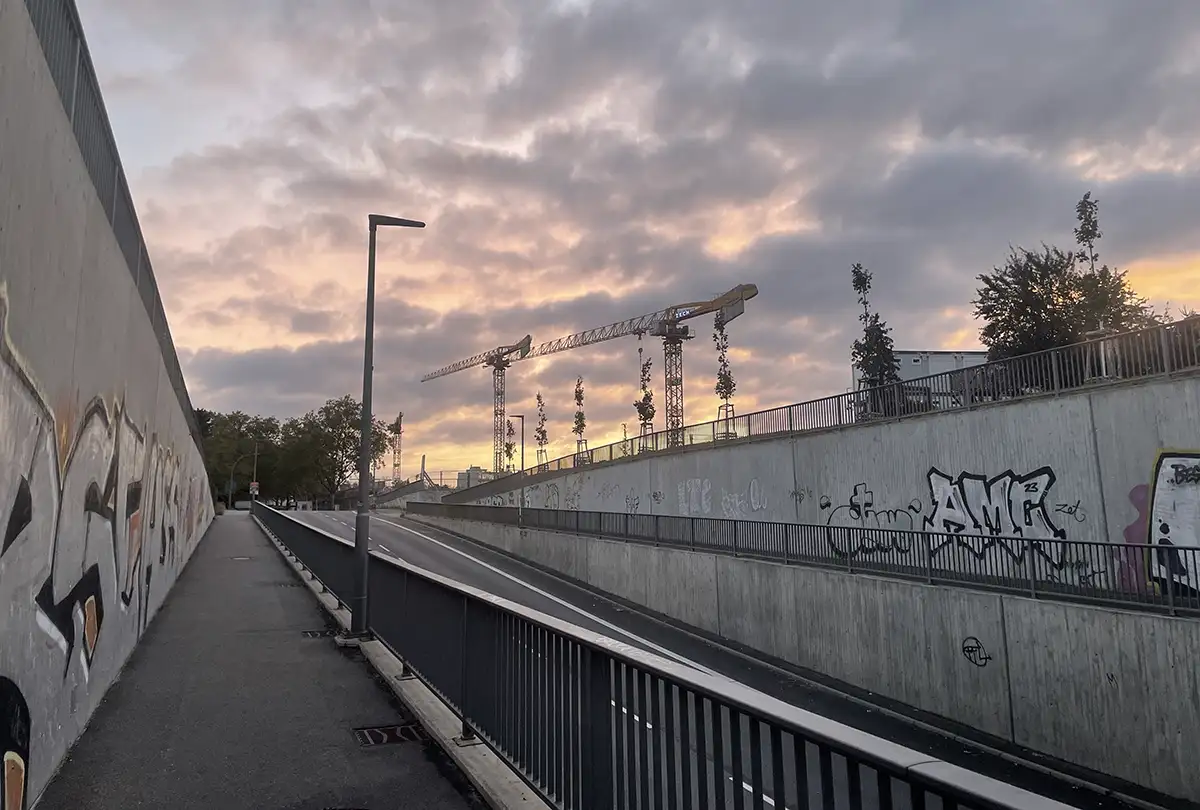 Unterführung mit Blick auf Baukrände vor wolkigem Morgenhimmel