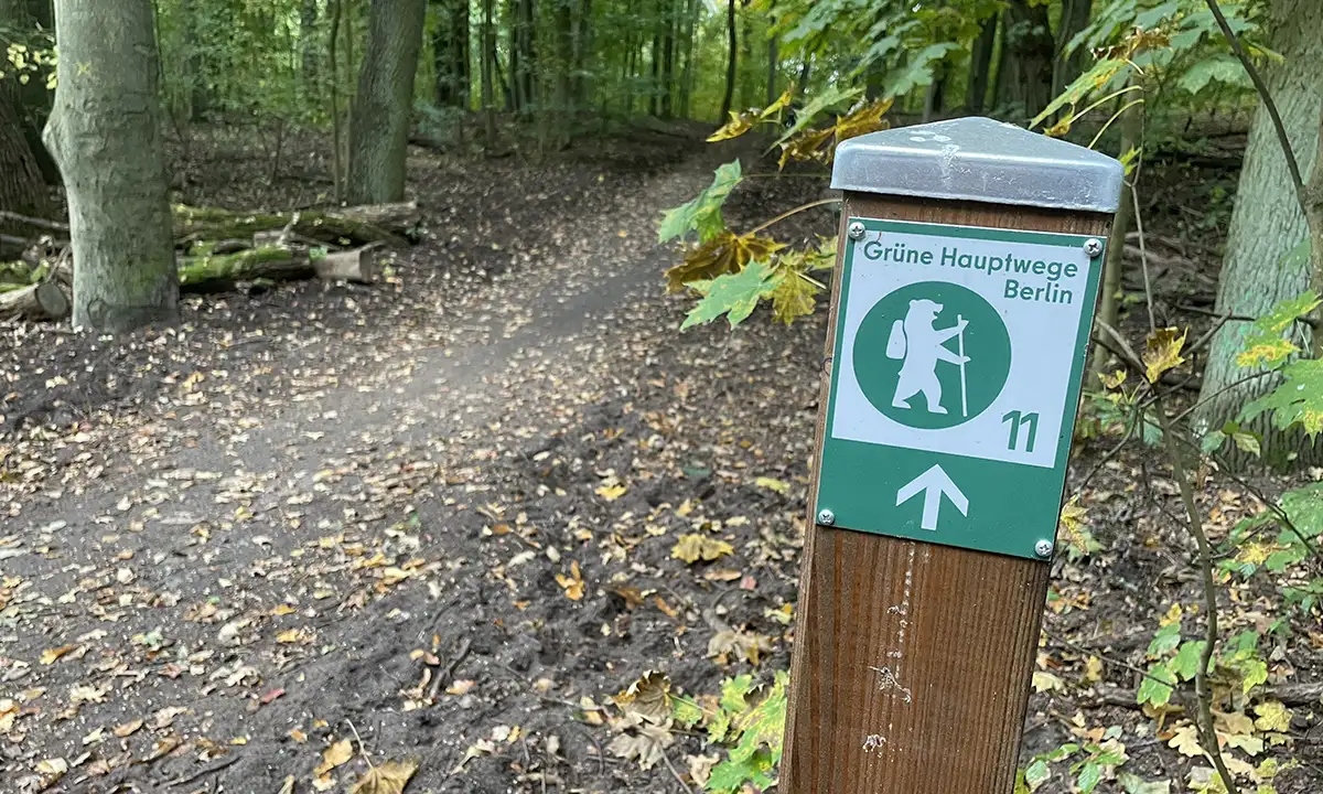 Schild an einem Holzpfosten „Grüne Hauptwege 11“