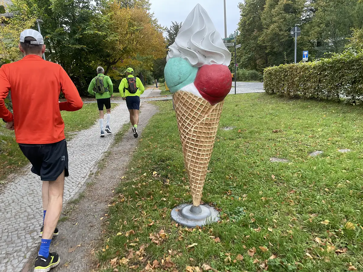 Läufer neben einer mannshohen Plastik-Eiswaffel mit Sahne