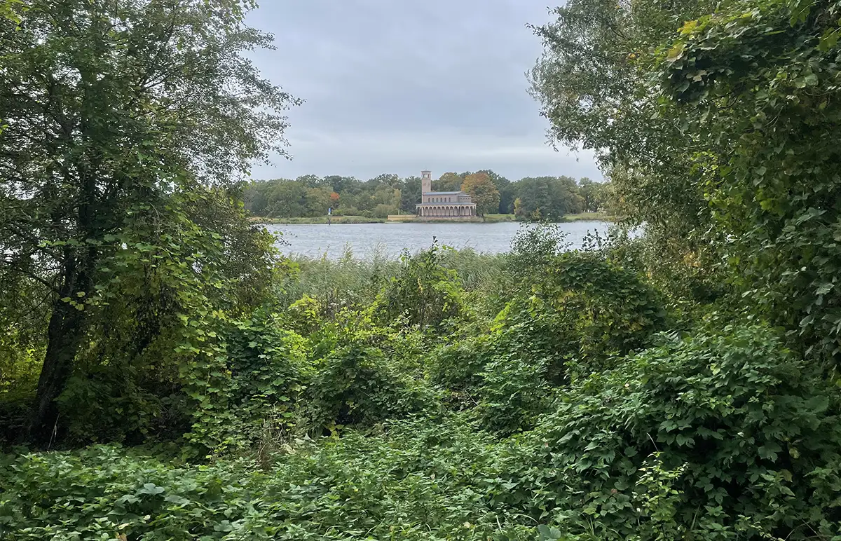 Blick über das grüne Ufer auf die Sacrower Heilandskirche auf der anderen Seite