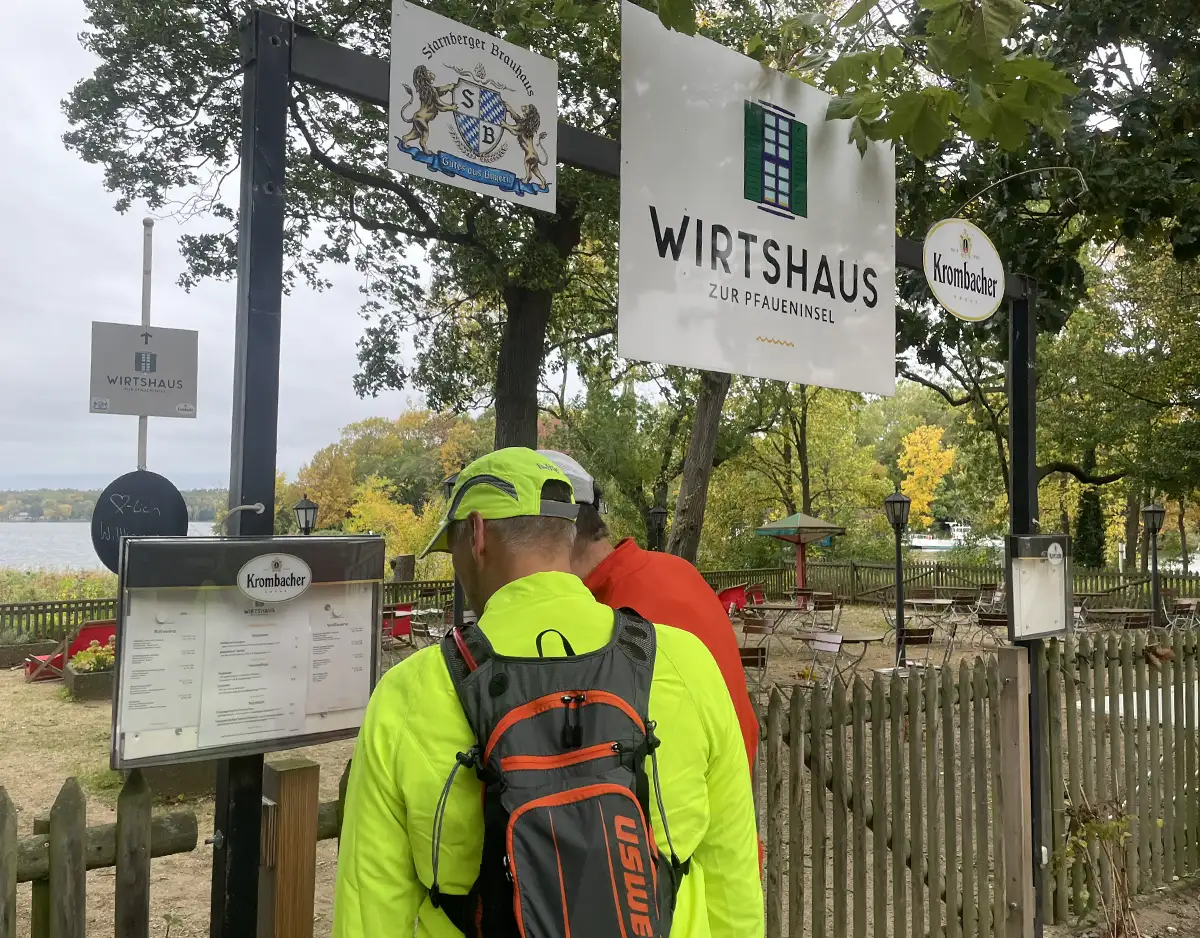 Läufer stehen am Biergarten und betrachten die Speisekarte