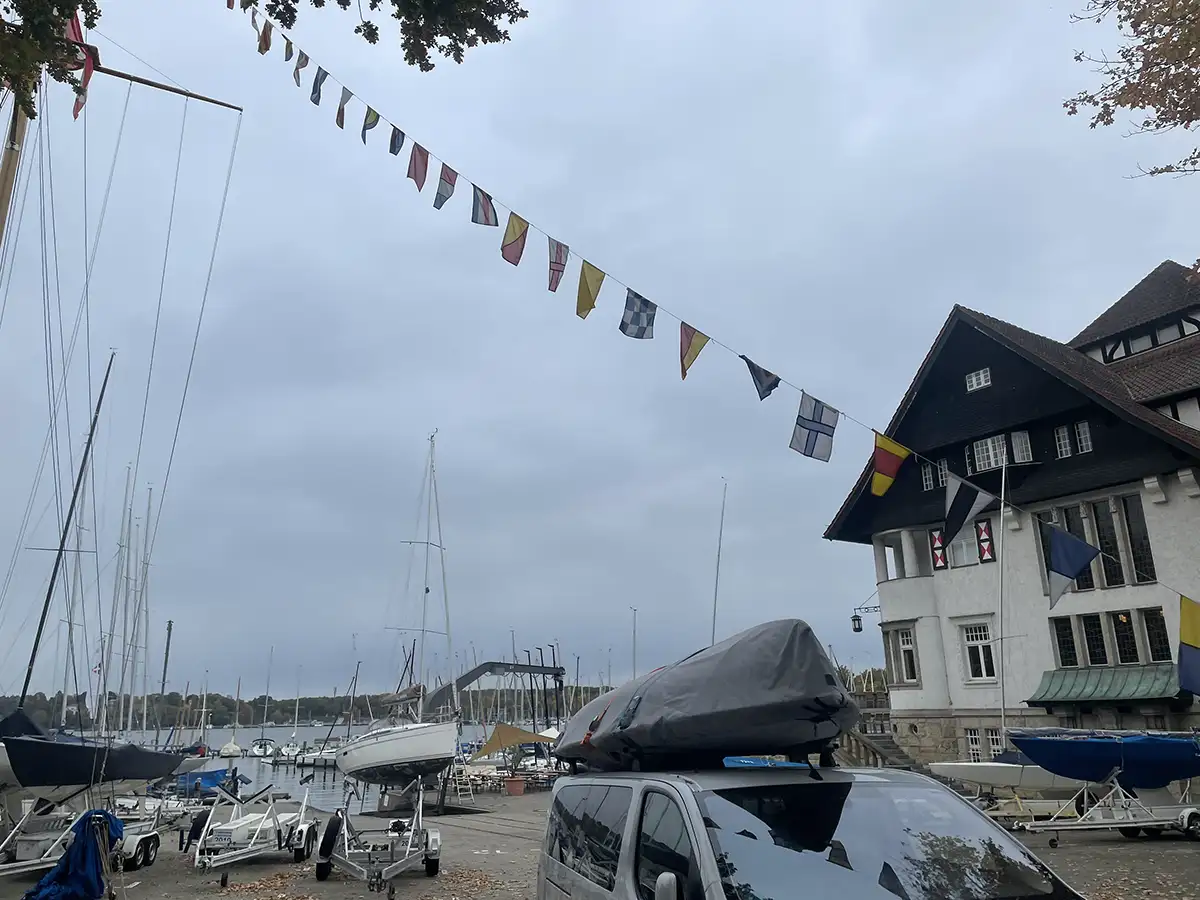 Gebäude eines Segelvereins, quer durch das Foto hängen maritime Fahnen an einem Seil