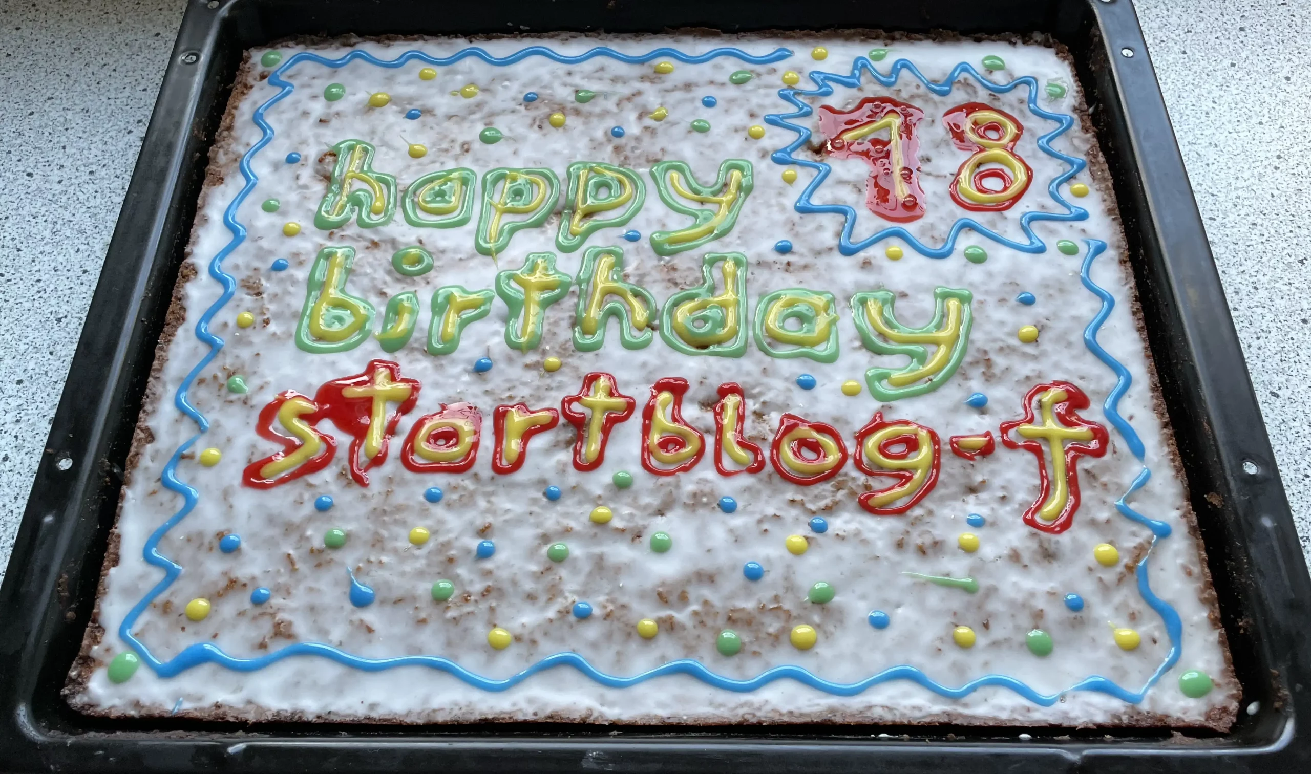 startblog-f-Kuchen auf einem Backblech, auf dem weißenb Zuckerguss steht „18 - happy birthday startblog-f“