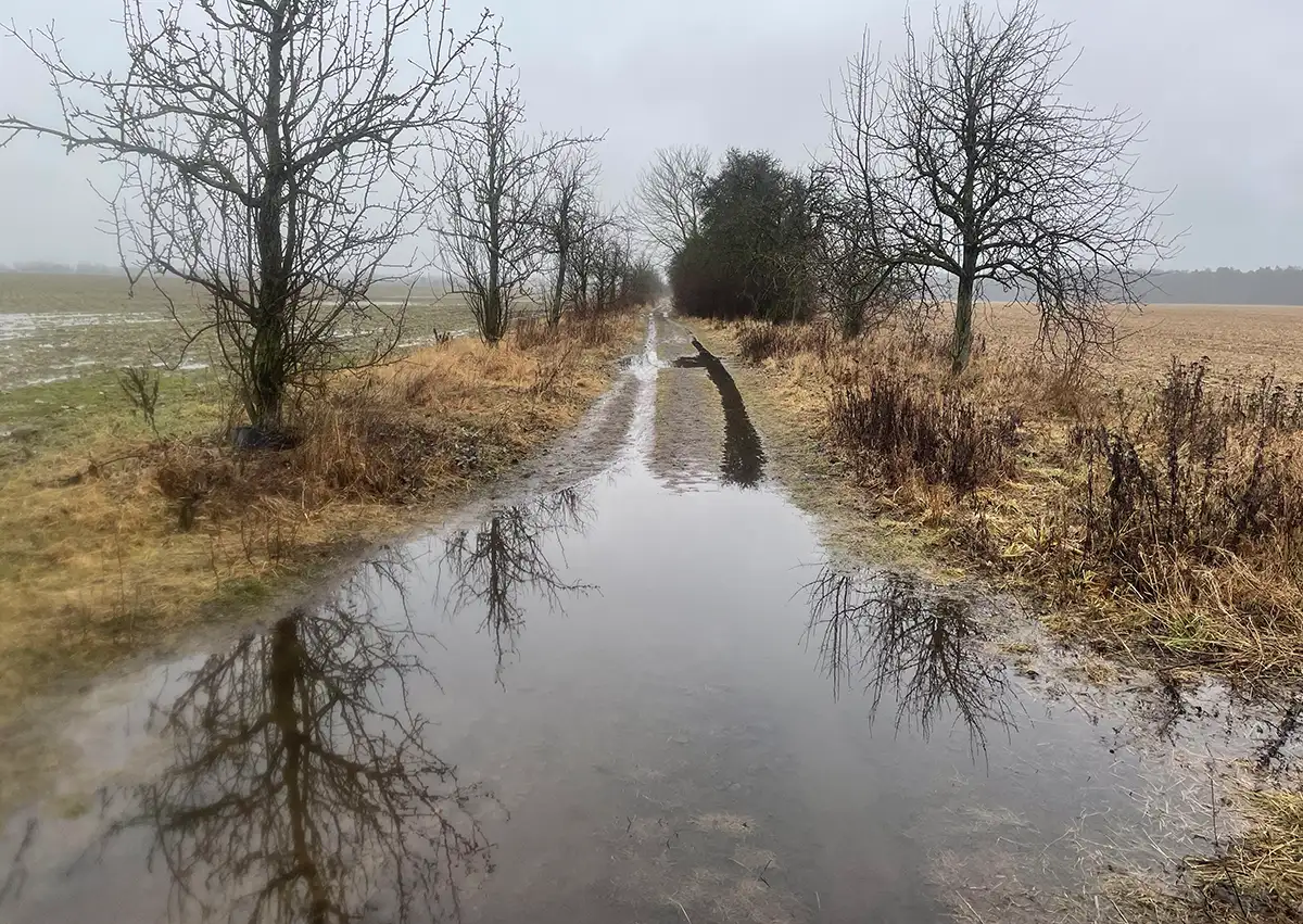 Große Pfütze quer über den breiten Feldweg