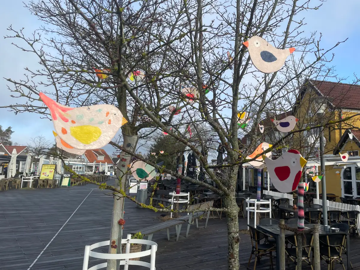 Bunt bemalte Holzvögel in den noch blattlosen Bäumen