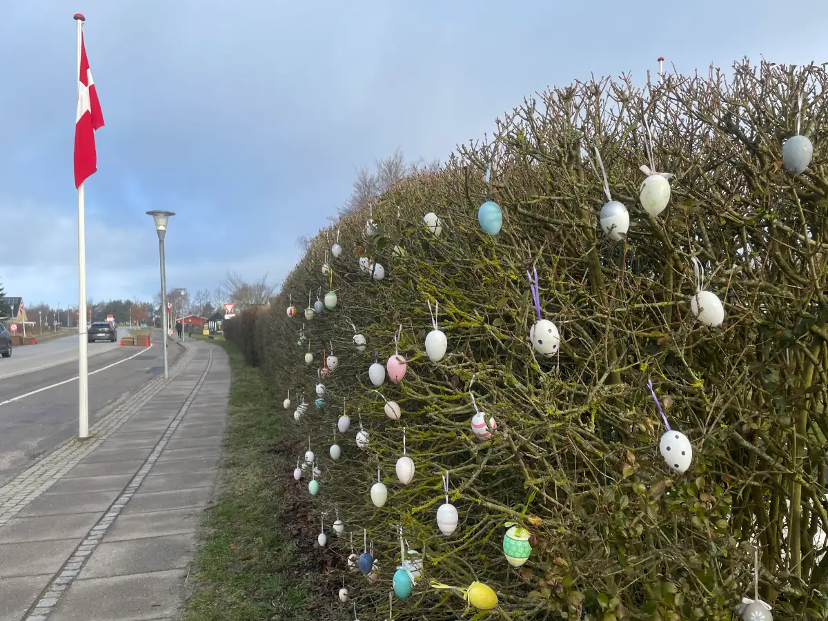 Bemalte Ostereier in einer Hecke am Fußweg