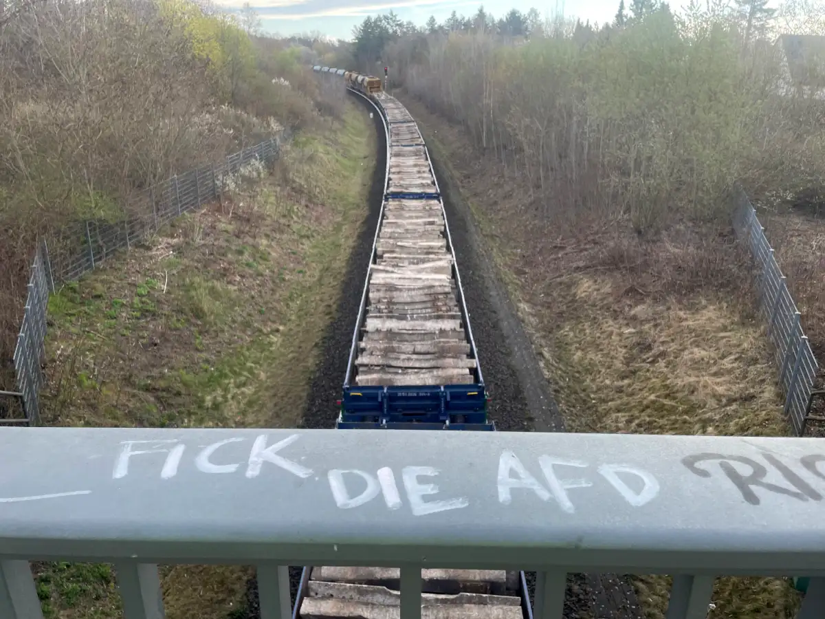 Blick von einer Brücke auf Zug-Waggons mit Holzbohlen
