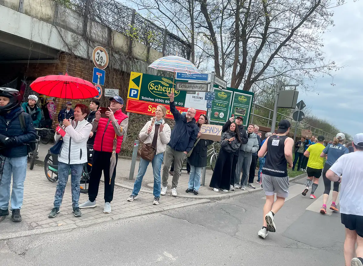 An einer Autobahnunterführung stehen Zuschauer mit Schirmen und fotografieren