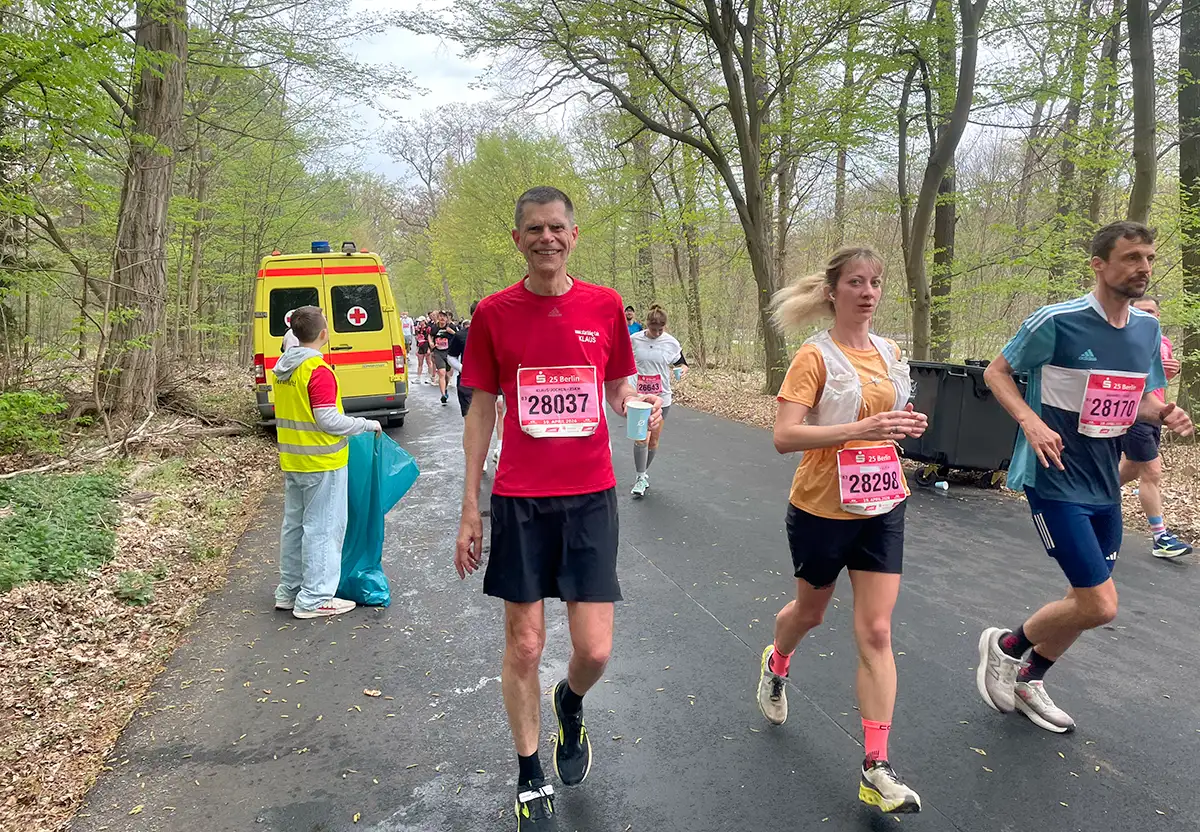 startblog-f-Läufer geht lächelnd an einem Getränkestand