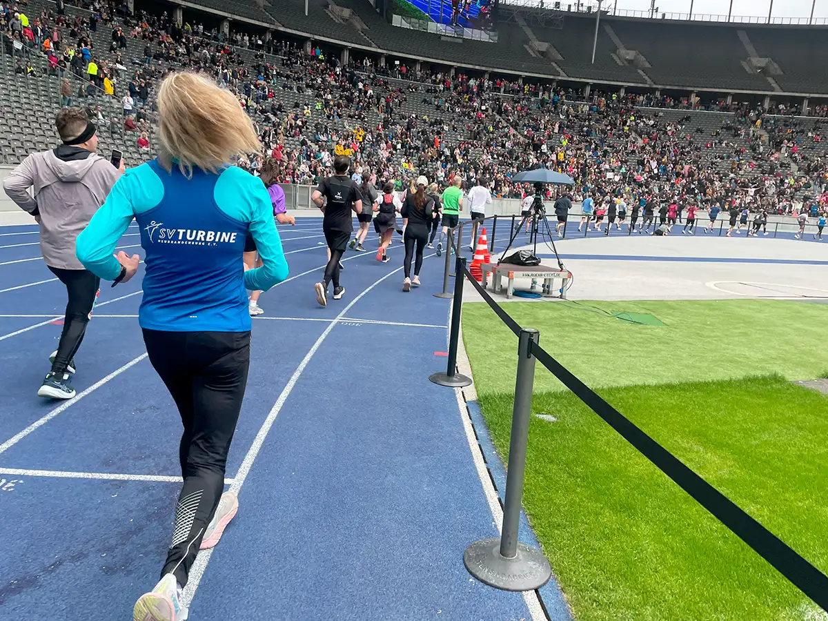 Läuferinnen und Läufer auf der blauen Bahn des Berliner Olympiastadions