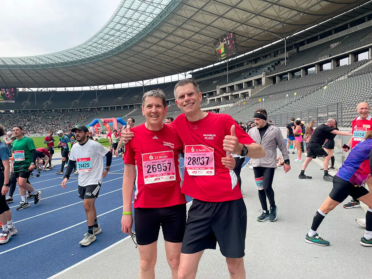 Lächelnde startblog-f-Läufer umarmen sich im Zielbereich