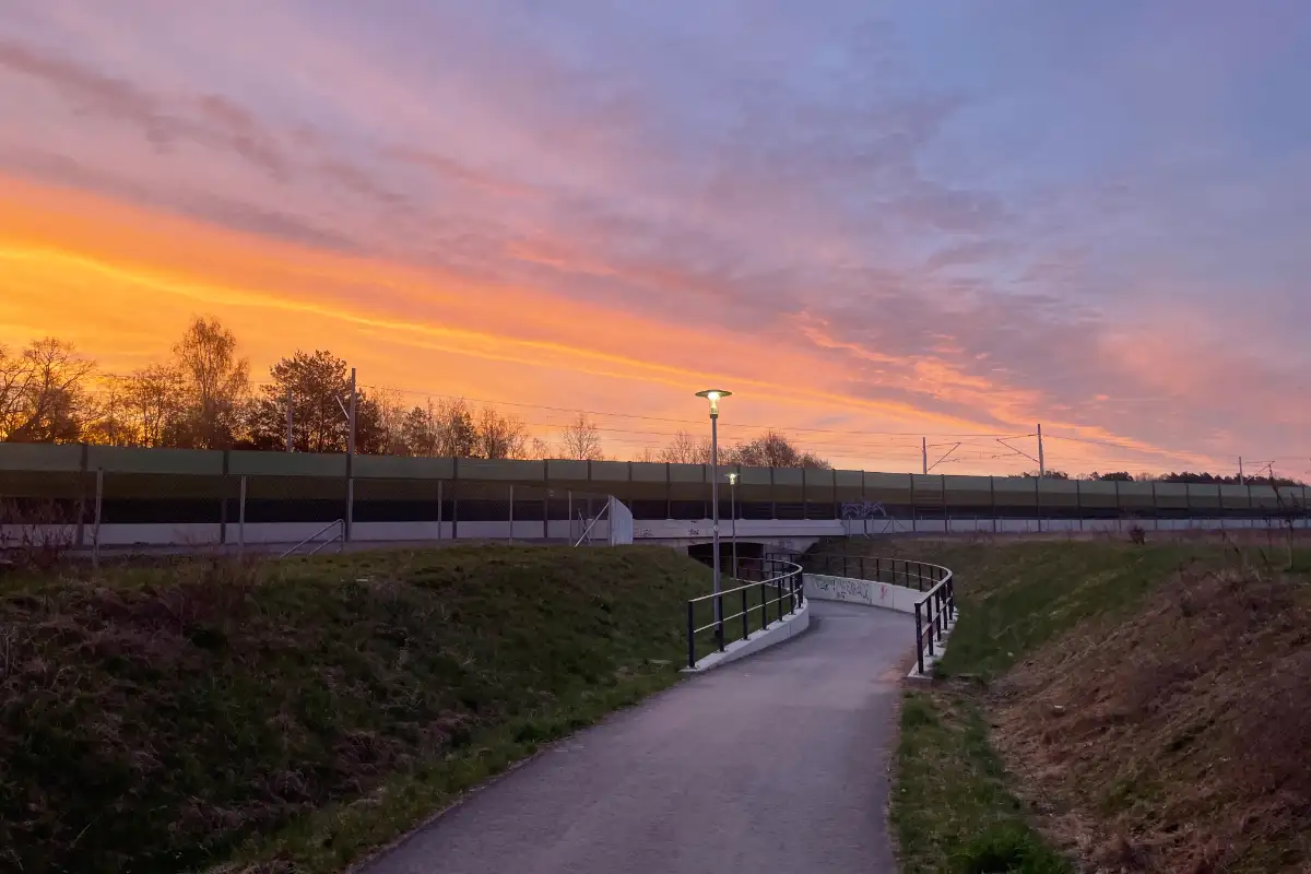 Rotvioletter Sonnenaufgang über einer Bahntrasse mit neuer Unterführung