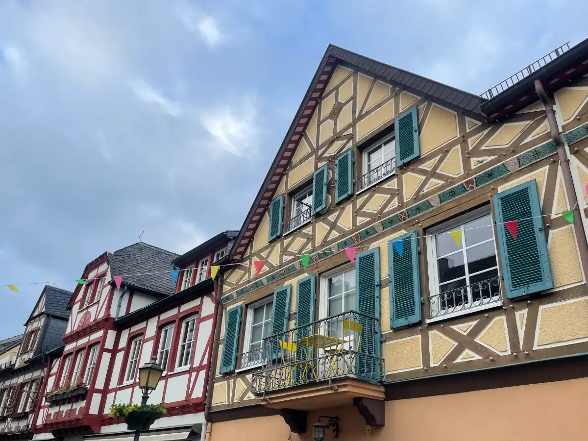 Giebel mehrerer Fachwerkhäuser, davor ein Band mit bunten Wimpeln