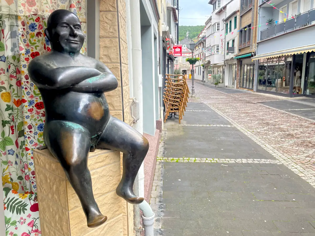 Skulpur eines nackten sitzenden Mannes in der Fußgängerzone