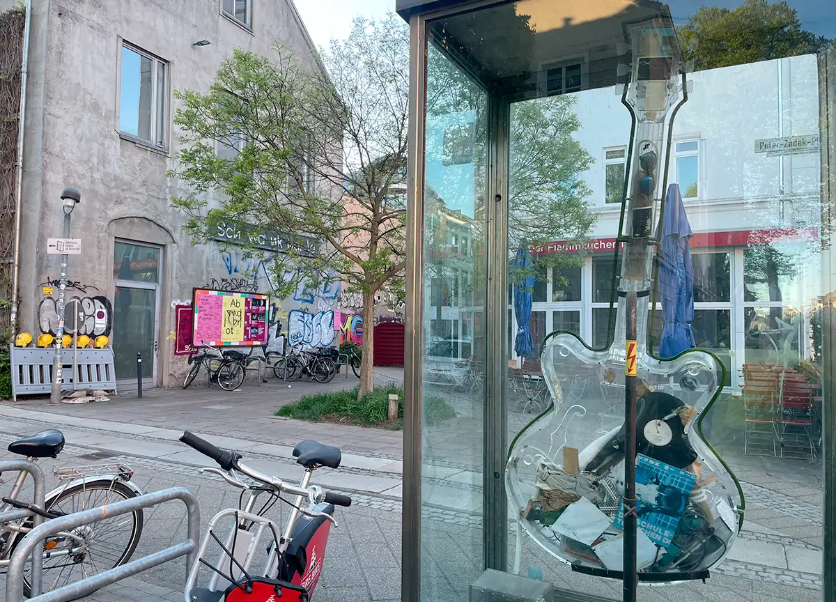 Modell einer durchsichtigen E-Gitarre in einem Glaskasten vor einem Gebäude