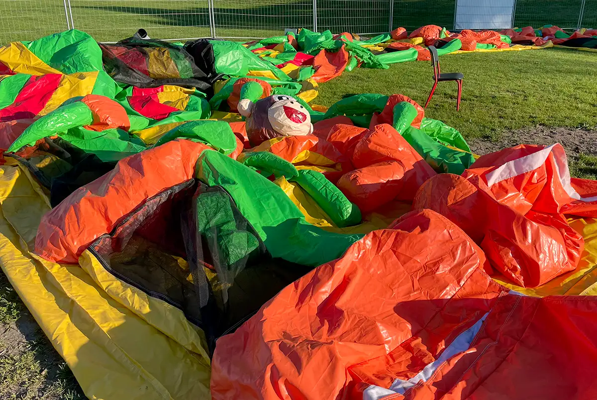 Bunte luftlose Plastikhülle einer Hüpfburg, darin ist ein Affengesicht zu erkennen